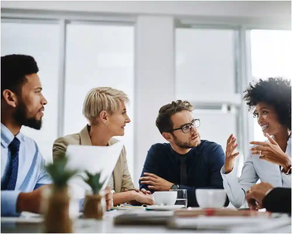 Four people sitting at a table discussing documents
