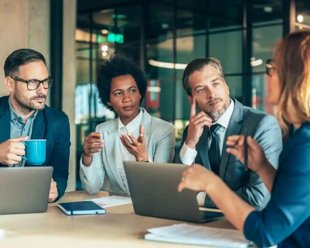 Four people with computers and documents having a discussion