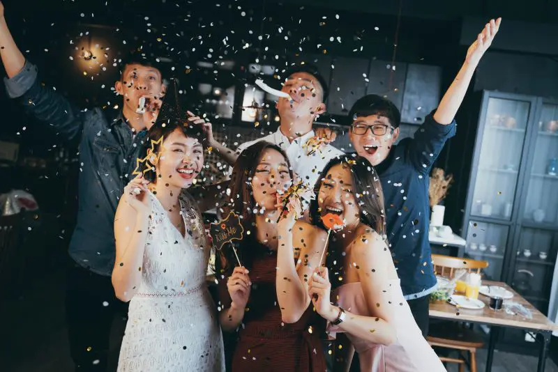 Asian friends celebrating with photo props and confetti