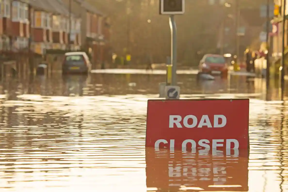 A street flooded with cars stuck and a "Road Closed" sign.