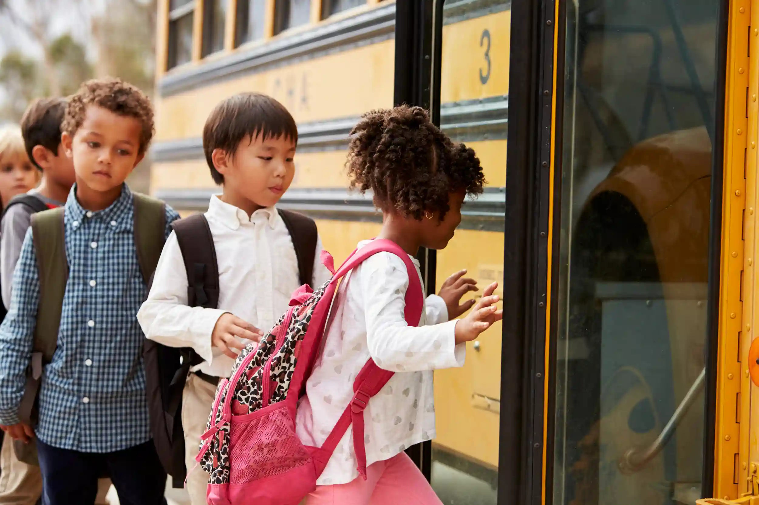 Children getting on a yellow school bus.