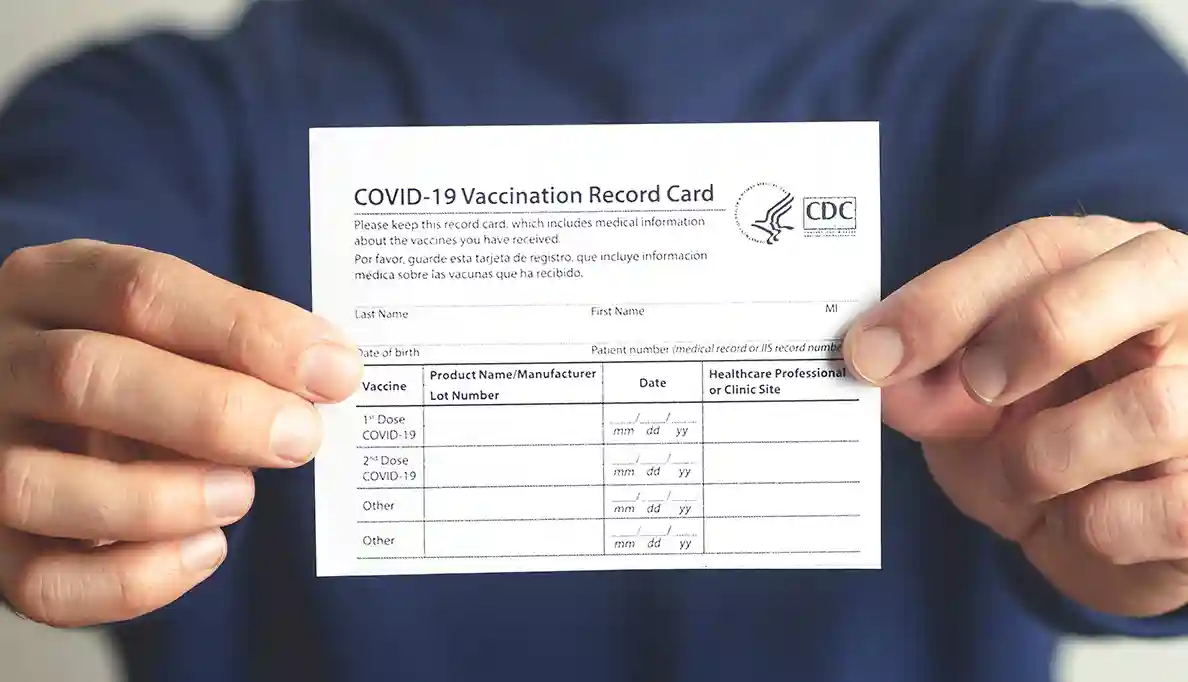 A close up of a person holding a COVID-19 vaccination card.