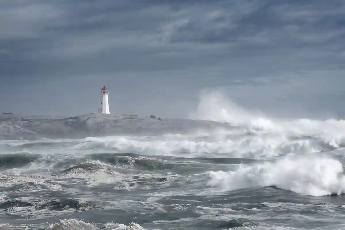 A hurricane creates rough seas along a coastline near a lighthouse.
