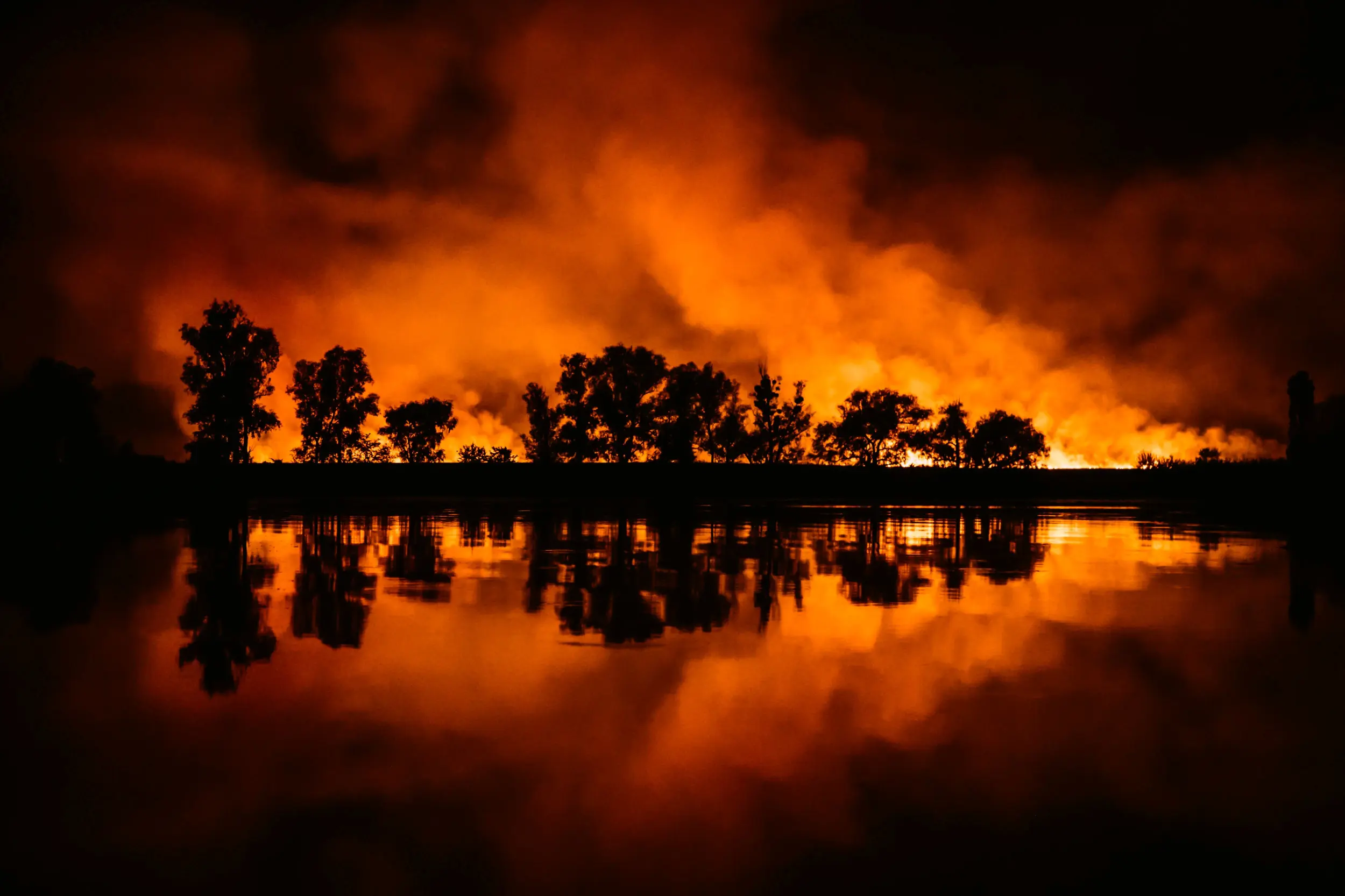 Night fire in the forest with reflection in river