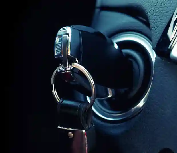 A key fob, with keychain, inserted into the ignition of a car.