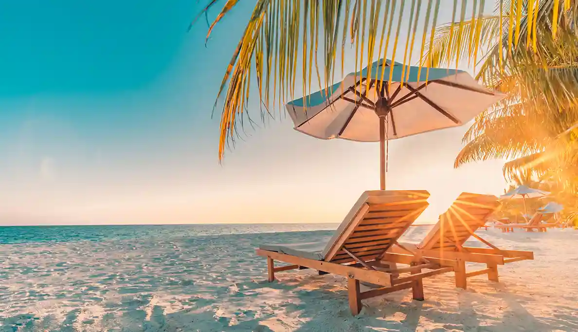 Two wooden slat reclining chairs and an umbrella on a sunny beach